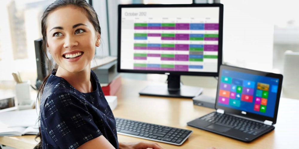 woman at desk in front of Dell laptop and monitor