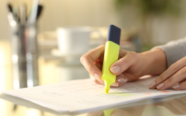 Woman's hand underlining text on a document with a highlighter.