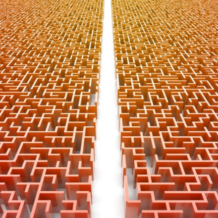 A clear path through the center of a maze with red walls on either side of the path.