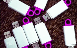 Several USB keys with white and magenta colors on a table.