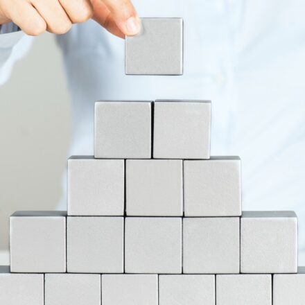 Woman building a pyramid wall with gray or silver cubes.