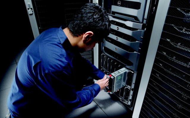 Man in blue shirt pulls a blade server out of server rack.
