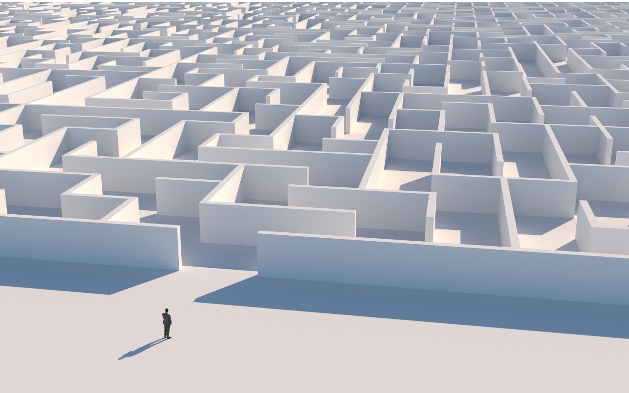 Digital rendering showing an aerial view of a business person standing before an entrance/exit to a labyrinth with what walls.